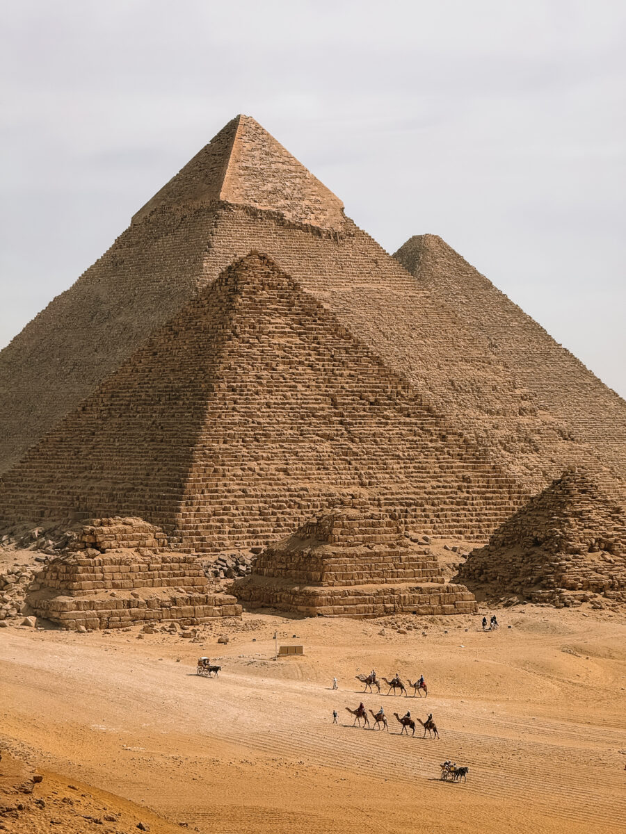 The Pyramids of Giza with a camel caravan crossing the desert, Egypt